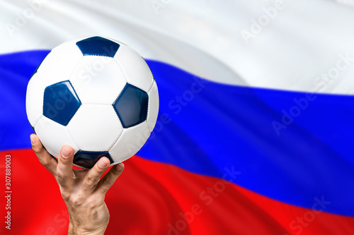 Russia soccer concept. National team player hand holding soccer ball with country flag background. Copy space for text.