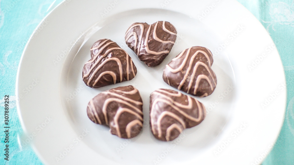 Christmas gingerbread in the form of hearts on a white plate and a blue tablecloth Christmas gingerbread in the form of hearts on a white plate and a blue tablecloth