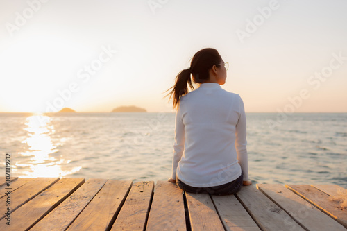 Lonely woman sitting on a wooden bridge sunset.are Lonely. during the time Sunset in winter photo