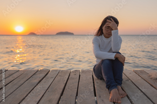 beautiful Lonely woman sitting on a wooden bridge sunset.are Lonely.Single women sat with stress