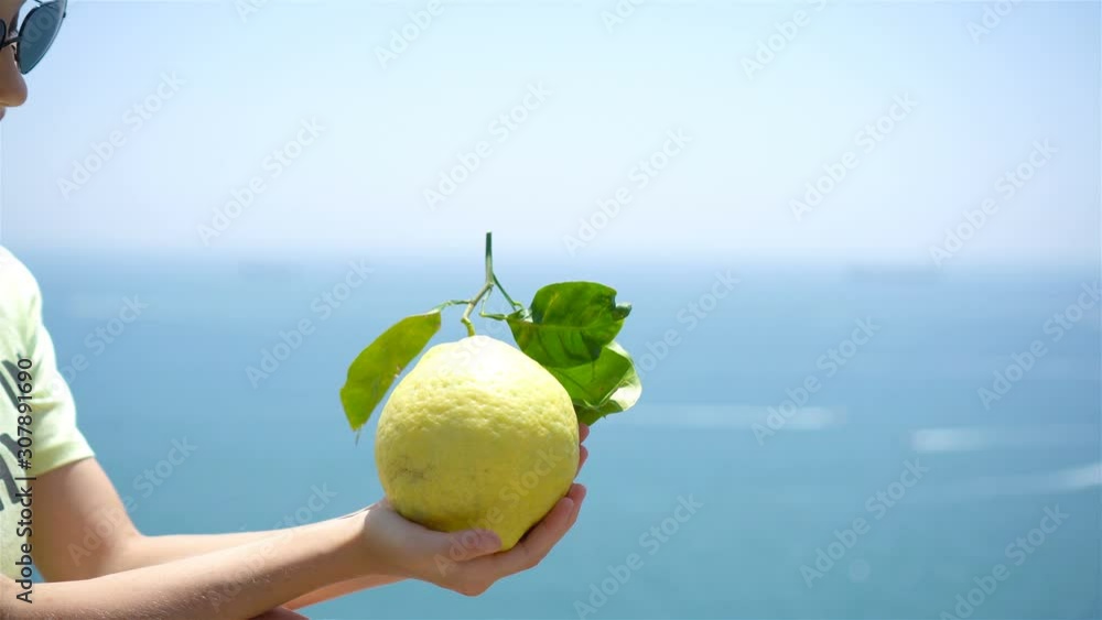 Big yellow lemon in hand in background of mediterranean sea and sky. Big yellow lemon in hand in background of mediterranean sea and sky.