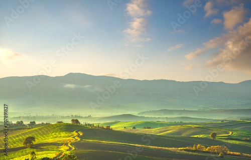 Tuscany countryside misty panorama, rolling hills and green fields on sunset. Pisa, Italy