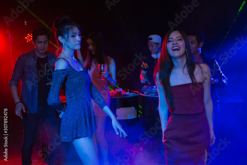 Holiday travel celebrations concept, group of people dancing together with enjoying at colourful night party club.