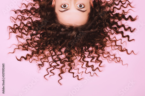 Big beautiful eyes of suprising young woman on pink background. Vertical photo, close up. photo