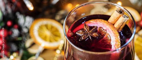 Bild auf Leinwand Christmas mulled close-up in a glass, red wine with spices and fruits oranges on a wooden rustic table with fir branches new year