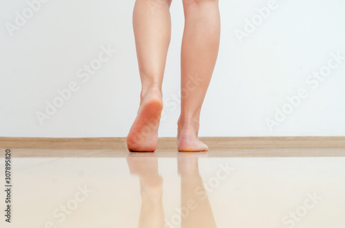 Female legs walk on warm floor of light yellow tiles