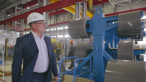 Satisfied businessman business owner in hard hat walking through heavy industry manufacturing plant facility