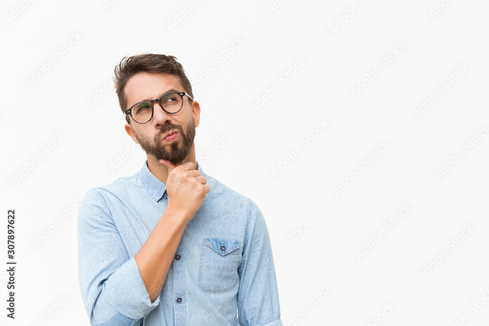 © Mangostar - Thoughtful male customer thinking hard, looking away at copy space, leaning chin on hand. Handsome young man in casual shirt and glasses standing isolated over white background. Special offer concept © Mangostar - Thoughtful male customer thinking hard, looking away at copy space, leaning chin on hand. Handsome young man in casual shirt and glasses standing isolated over white background. Special offer concept