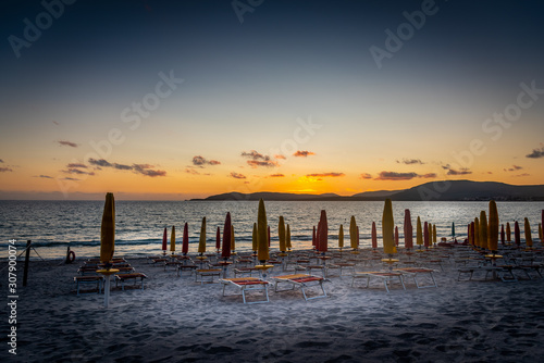 Beach chairs and parasols under a clear sky at sunset