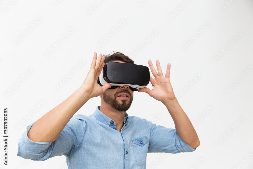 Bearded male user in VR glasses enjoying experience. Young man in virtual reality headset standing isolated over white background. VR game test concept Bearded male user in VR glasses enjoying experience. Young man in virtual reality headset standing isolated over white background. VR game test concept