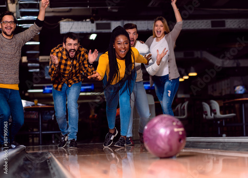 Group of friends enjoying time together laughing and cheering while bowling at club. photo