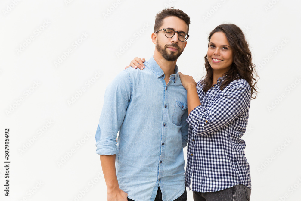 Sweet couple hugging and posing for camera. Young woman in casual and man in glasses standing isolated over white background. Advertising concept Sweet couple hugging and posing for camera. Young woman in casual and man in glasses standing isolated over white background. Advertising concept