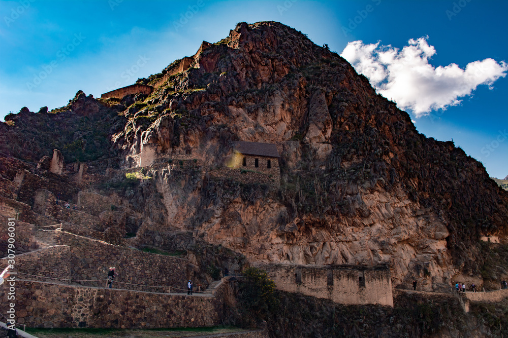 Mountain of Ollantaytambo ruins in Cusco with tourists walking.