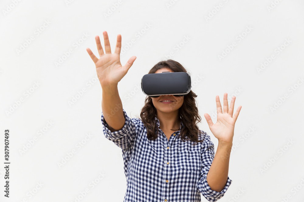 Happy student girl in VR goggles touching air. Young woman in virtual reality headset standing isolated over white background. VR experience concept Happy student girl in VR goggles touching air. Young woman in virtual reality headset standing isolated over white background. VR experience concept