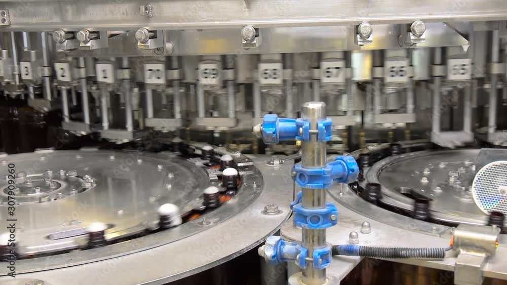 Beer fills bottles in the workshop, on specialized equipment. Beer in brown plastic bottles on the conveyor. Shop for bottling beer in a brewery. Shop for bottling and packaging beer. Beer fills bottles in the workshop, on specialized equipment. Beer in brown plastic bottles on the conveyor. Shop for bottling beer in a brewery. Shop for bottling and packaging beer.
