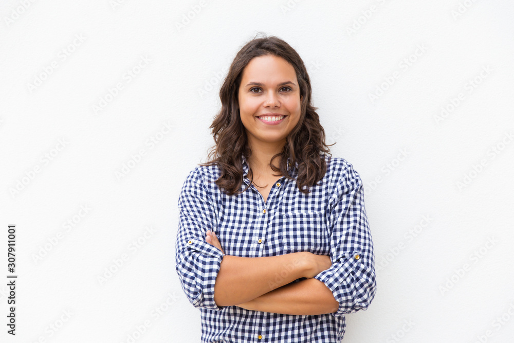 Happy joyful student girl with arms folded looking at camera and smiling. Young woman in casual checked shirt standing isolated over white background. Female portrait concept Happy joyful student girl with arms folded looking at camera and smiling. Young woman in casual checked shirt standing isolated over white background. Female portrait concept