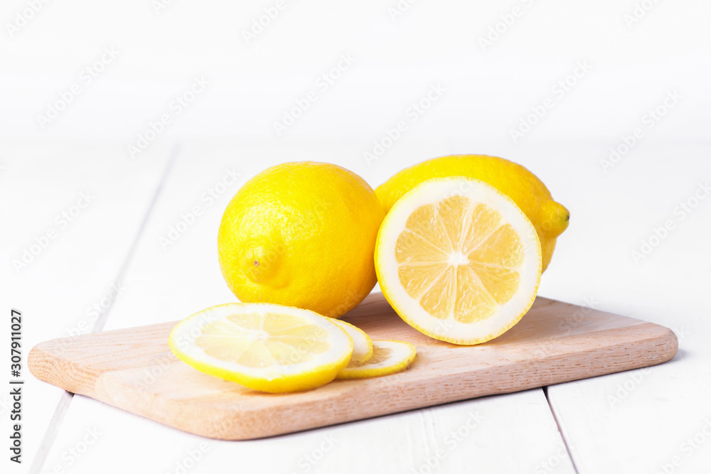Ripe full yellow lemon citrus fruit with lemon half and lemon's slicees on white wooden background. Full depth of field. Copy space Ripe full yellow lemon citrus fruit with lemon half and lemon's slicees on white wooden background. Full depth of field. Copy space