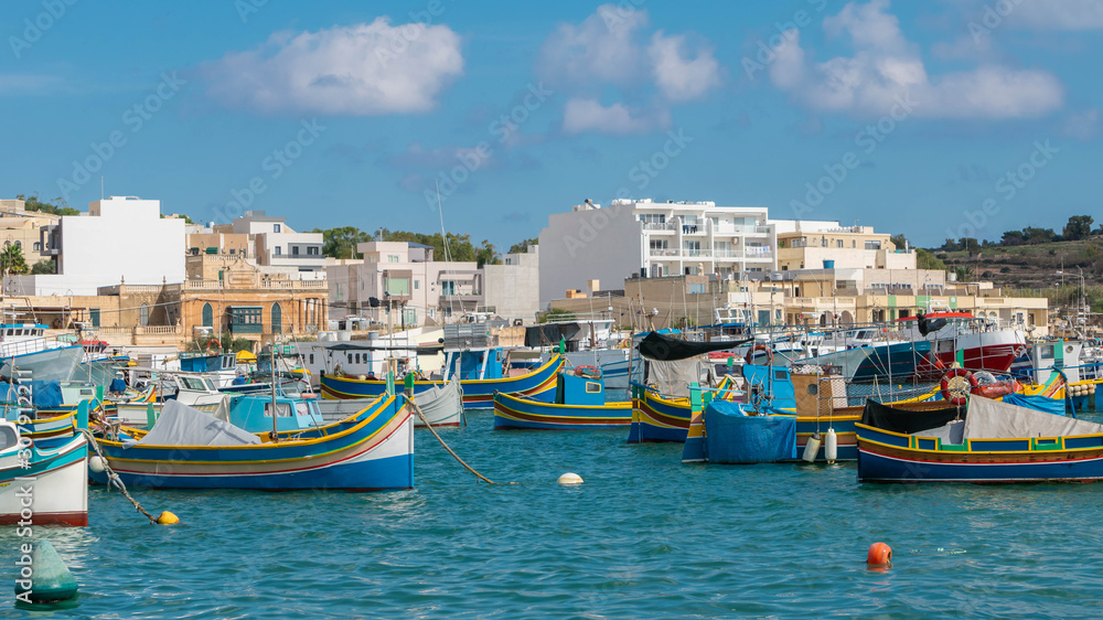 Colorful, traditional fishing boats in Marsaxlokk village harbor of Mediterranean island of Malta