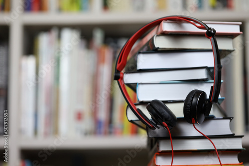 headphones and a stack of books, listening to audio books and traditional reading