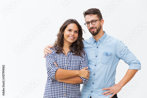 Cheerful couple hugging and posing. Young woman in casual and man in glasses standing isolated over white background. Happy young couple concept
