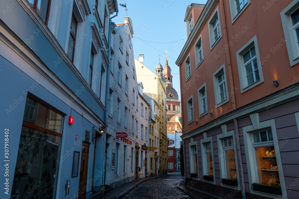 Riga / Latvia - 03 December 2019:Narrow cobblestone street to Dome Cathedral in Riga, Latvia.