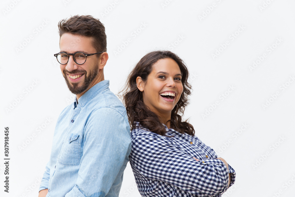Happy cheerful couple leaning on each other, laughing and looking at camera. Young woman in casual and man in glasses in glasses posing isolated over white background. Close friendship concept Happy cheerful couple leaning on each other, laughing and looking at camera. Young woman in casual and man in glasses in glasses posing isolated over white background. Close friendship concept