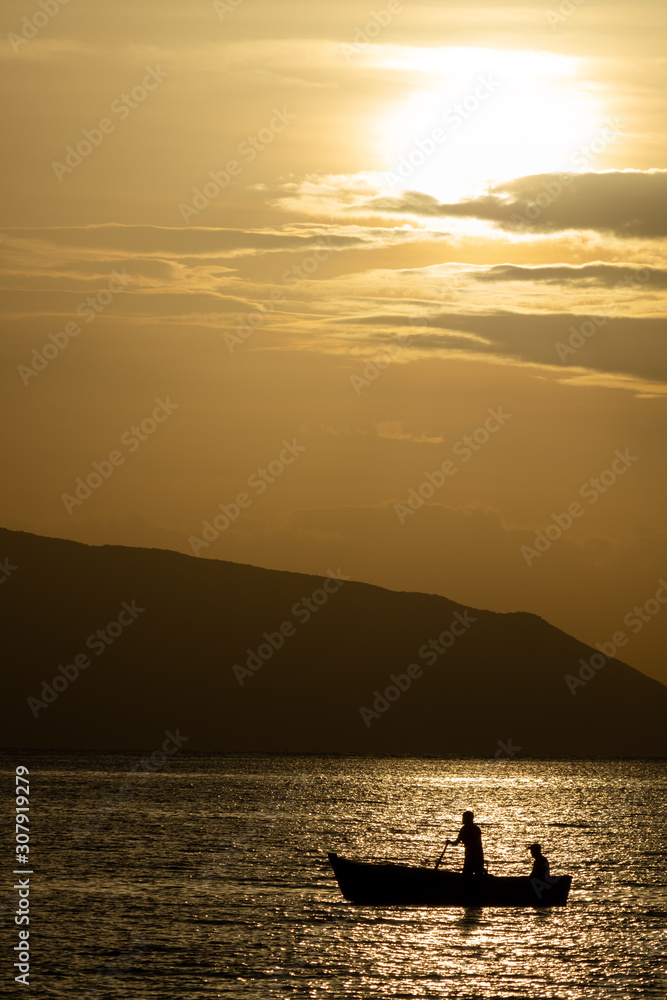 Sunrise seascape with mountains and fisherman boat