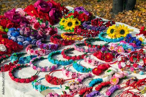 Wreaths on the head of colorful flowers. Table with many colorful flowers and wreaths © Klochkov