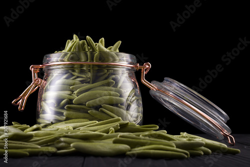 Jar of foglie spinach pasta on wooden table isolated on black background photo