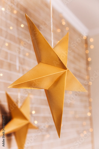 Paper Christmas hand made yellow star decor on the brick wall.Christmas interior decoration.Holidays,Christmas and New Year concept. Scandinavian Style.