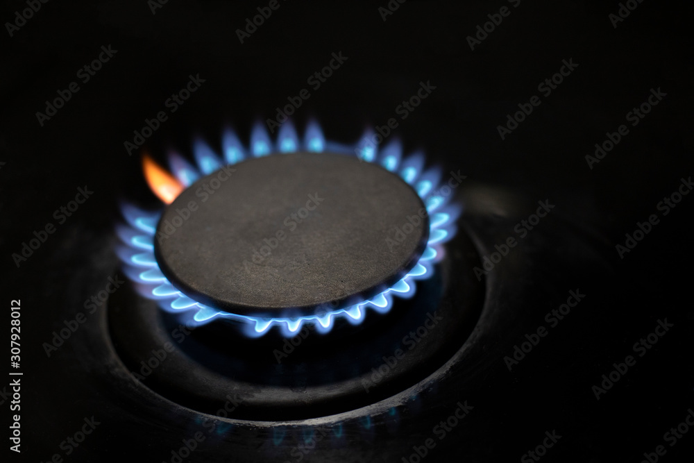 Burner with flame in the dark, closeup. Blue and red flame. Gas supply to consumers. Burner with flame in the dark, closeup. Blue and red flame. Gas supply to consumers.