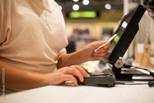 Young woman hands scaning / entering discount / sale on a receipt, touchscreen cash register, market / shop, finance concept, business © Khaligo