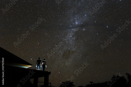 Fototapeta Naklejka Na Ścianę i Meble -  Couple on rooftop watching mliky way and stars in the night sky on Bali island.