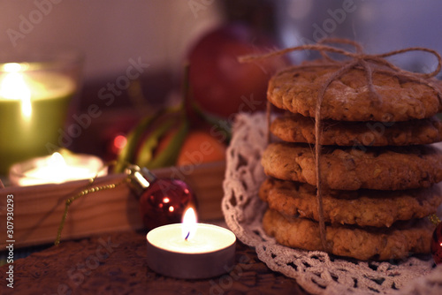 Christmas cookies on the rustic napkin with candles, New Year decorarion and some fruits