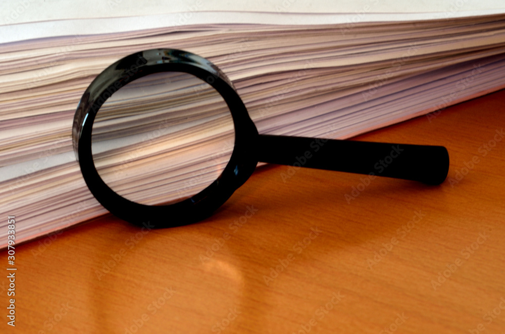 Fototapeta premium Paper Stack and Magnifying Glass