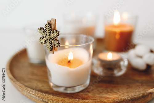 Wooden tray with burning candles standing on white table. Cozy home decoration  interior decor. White background  copy space  selective focus.