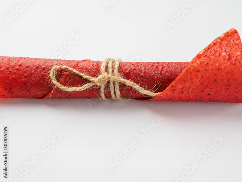 Red strawberry fruit leather roll lie on white background photo