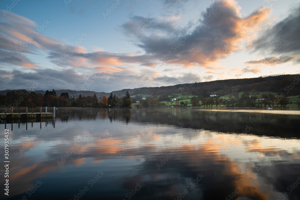 Stuning Autumn Fall sunrise landscape over Coniston Water with mist and wispy clouds