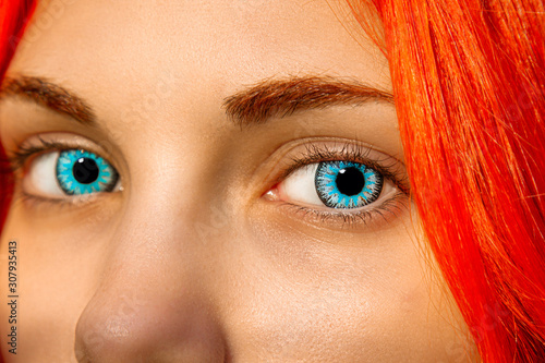 A closeup of an eye with large, bright blue lenses. Eyelashes and pupil close-up. Red hair and eyebrows, soulful look. photo