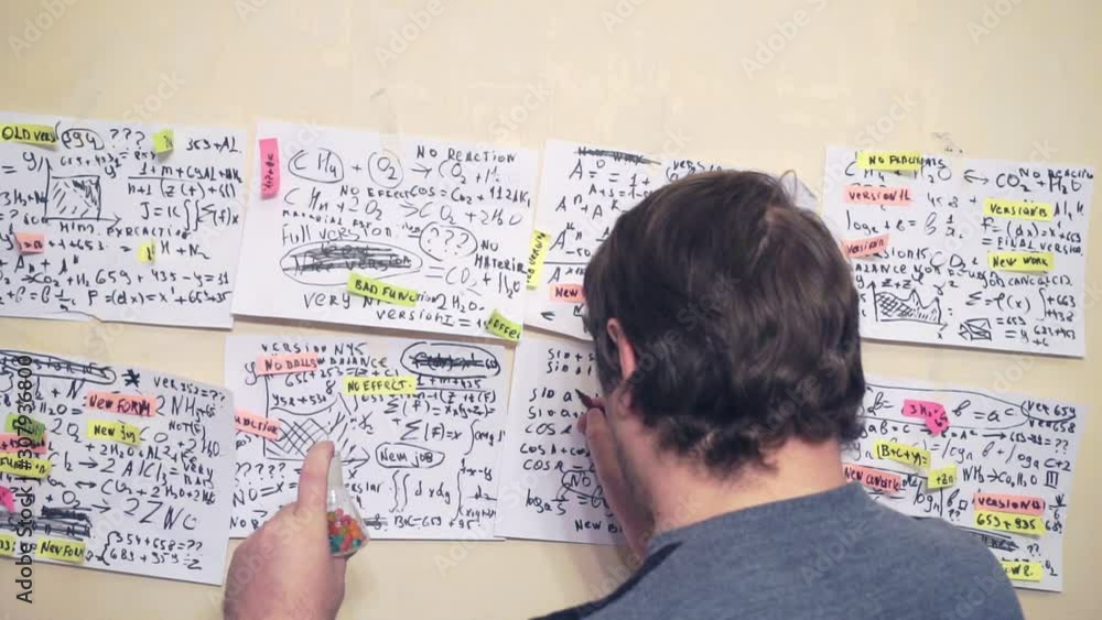 researcher works with various formulas and calculations on paper sheets that hang on the wall.research work.scientist in the workplace researcher works with various formulas and calculations on paper sheets that hang on the wall.research work.scientist in the workplace
