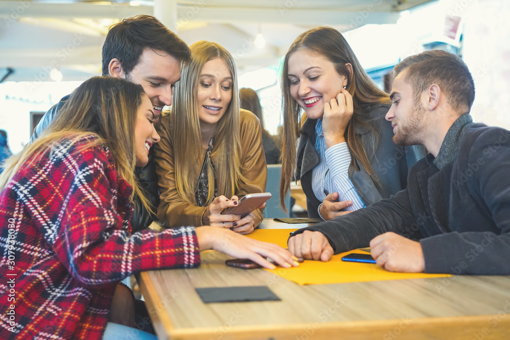 Group of teenagers hangging out in a bar and using smartphones- Girl showing her friends the new online stuff like photo, video, tik tok- Obsessed in technology concept Group of teenagers hangging out in a bar and using smartphones- Girl showing her friends the new online stuff like photo, video, tik tok- Obsessed in technology concept