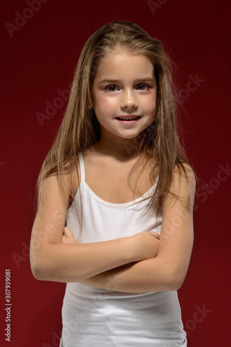 portrait of a little beautiful girl in a white T-shirt on a black background. Emotions