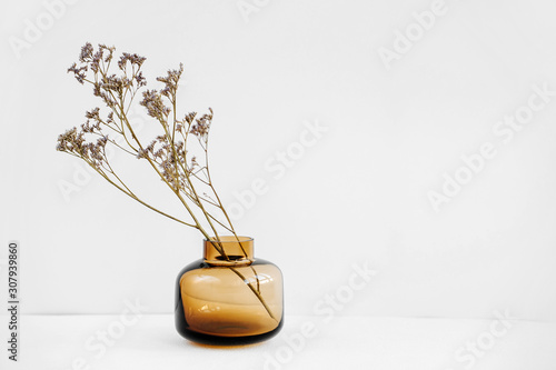 Foto Branch flowers in a glass vase on white table