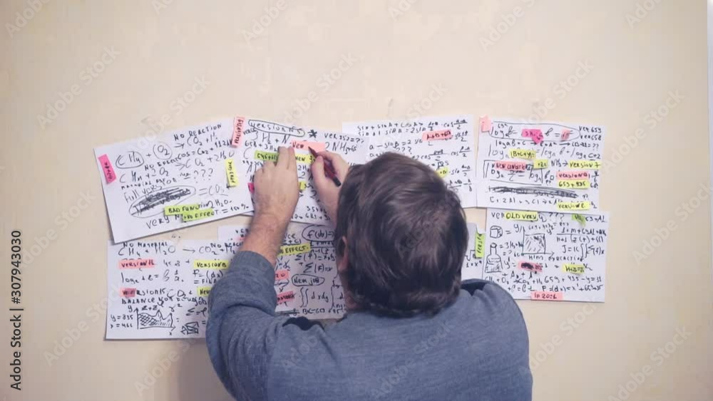 researcher works with various formulas and calculations on paper sheets that hang on the wall.research work.scientist in the workplace. researcher works with various formulas and calculations on paper sheets that hang on the wall.research work.scientist in the workplace.