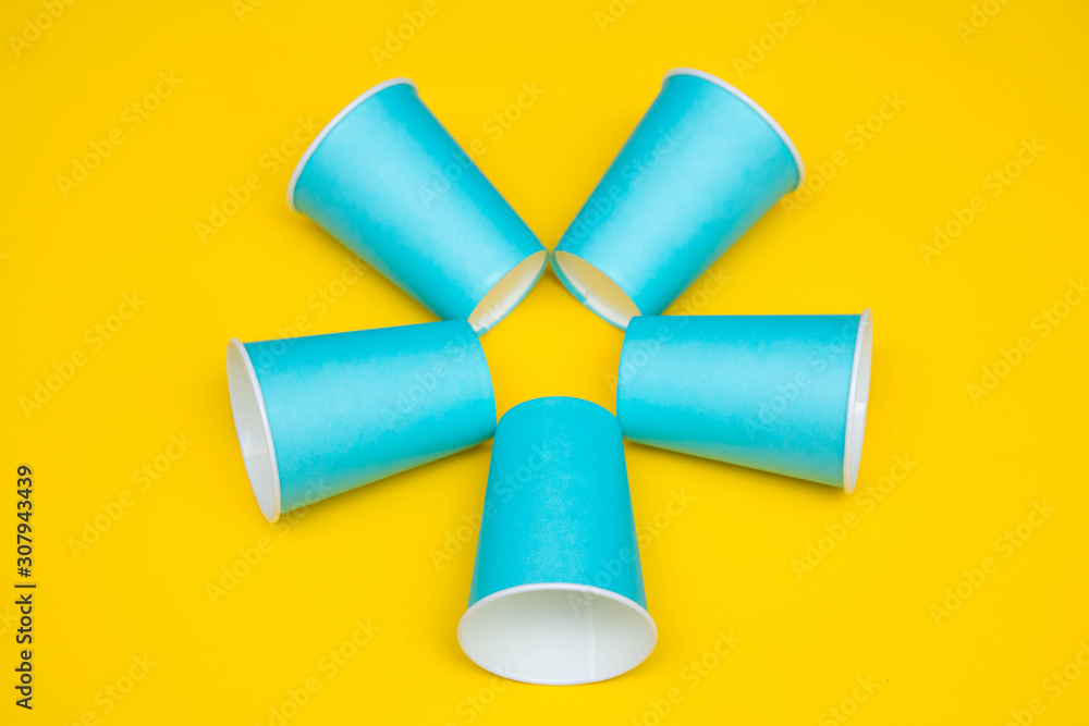 Pattern from blue paper disposable cups on yellow background. Set for party. Top view. Minimalist Style. Copy, empty space for text Pattern from blue paper disposable cups on yellow background. Set for party. Top view. Minimalist Style. Copy, empty space for text