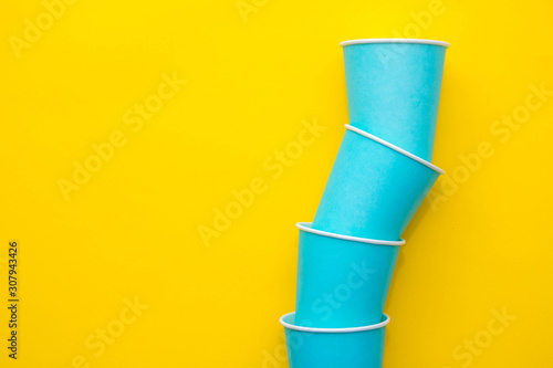 Blue paper disposable cups on yellow background. Set for party. Top view. Minimalist Style. Copy, empty space for text © Andriy