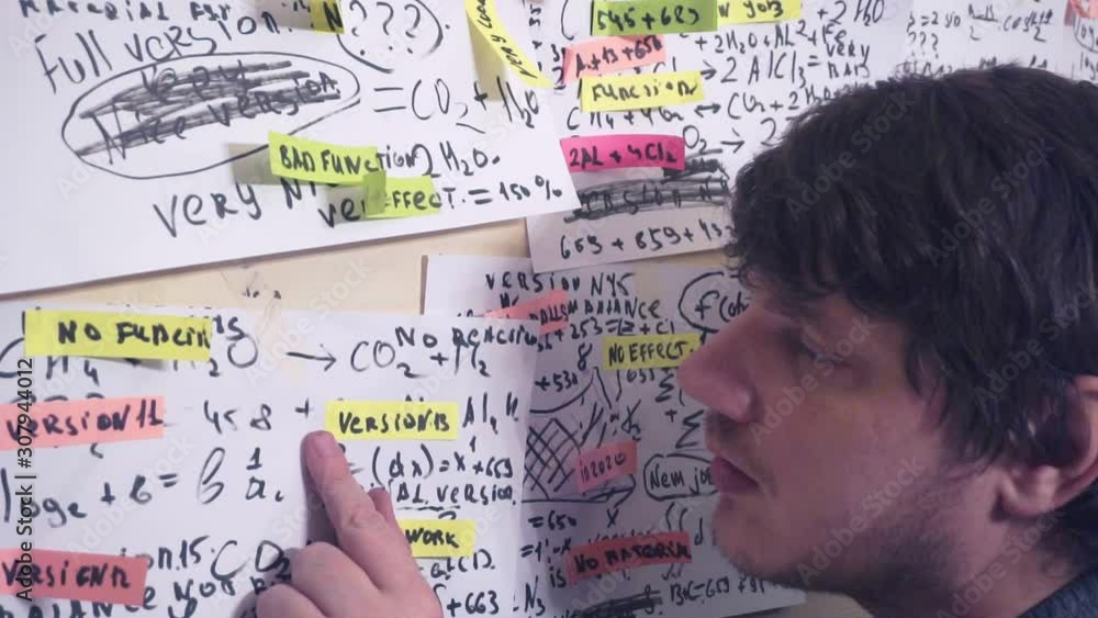 middle-aged man works with information on paper sheets that hang on the wall.scientific and research work.teacher at the workplace middle-aged man works with information on paper sheets that hang on the wall.scientific and research work.teacher at the workplace