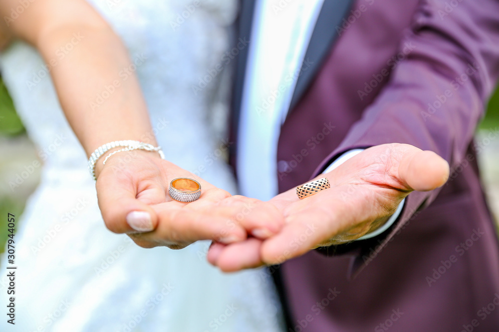 Fototapeta premium two wedding rings in the hands of the newlyweds gold wedding rings wedding rings of precious metal on the hands of a man and a woman wedding ceremony. 