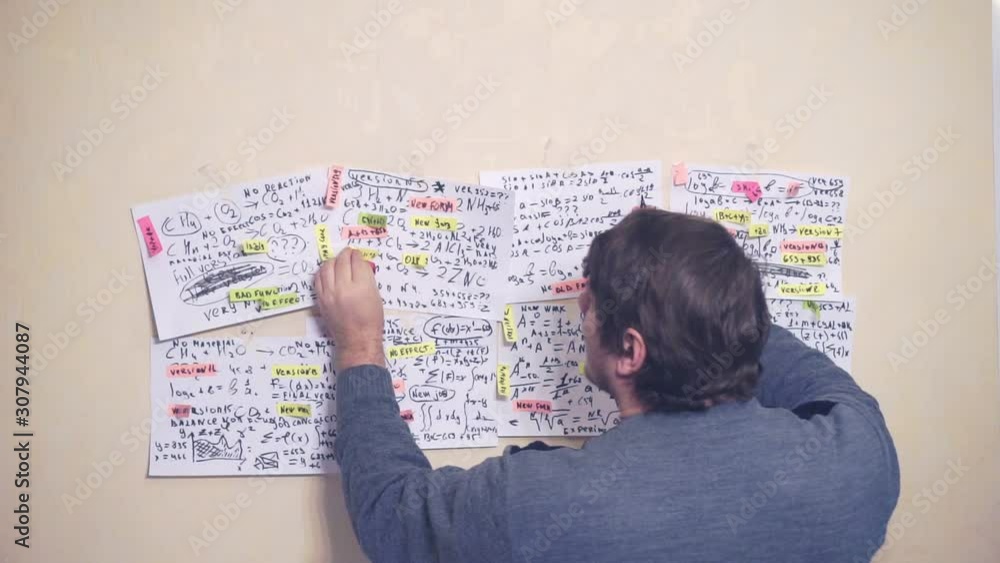 middle-aged man works with information on paper sheets that hang on the wall.scientific and research work.teacher at the workplace middle-aged man works with information on paper sheets that hang on the wall.scientific and research work.teacher at the workplace