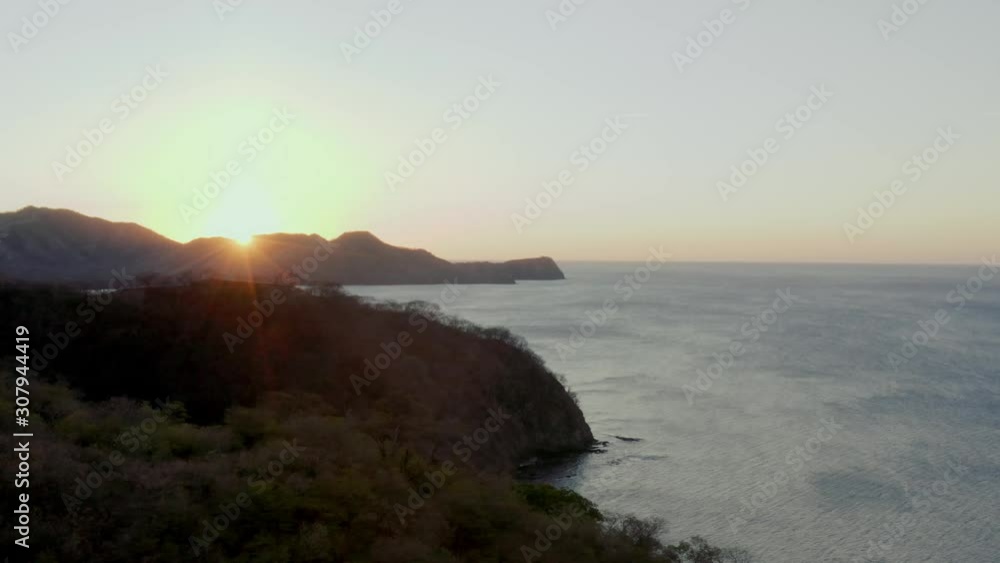 Drone shot rising above a tropical hillside during golden hour sunset Drone shot rising above a tropical hillside during golden hour sunset